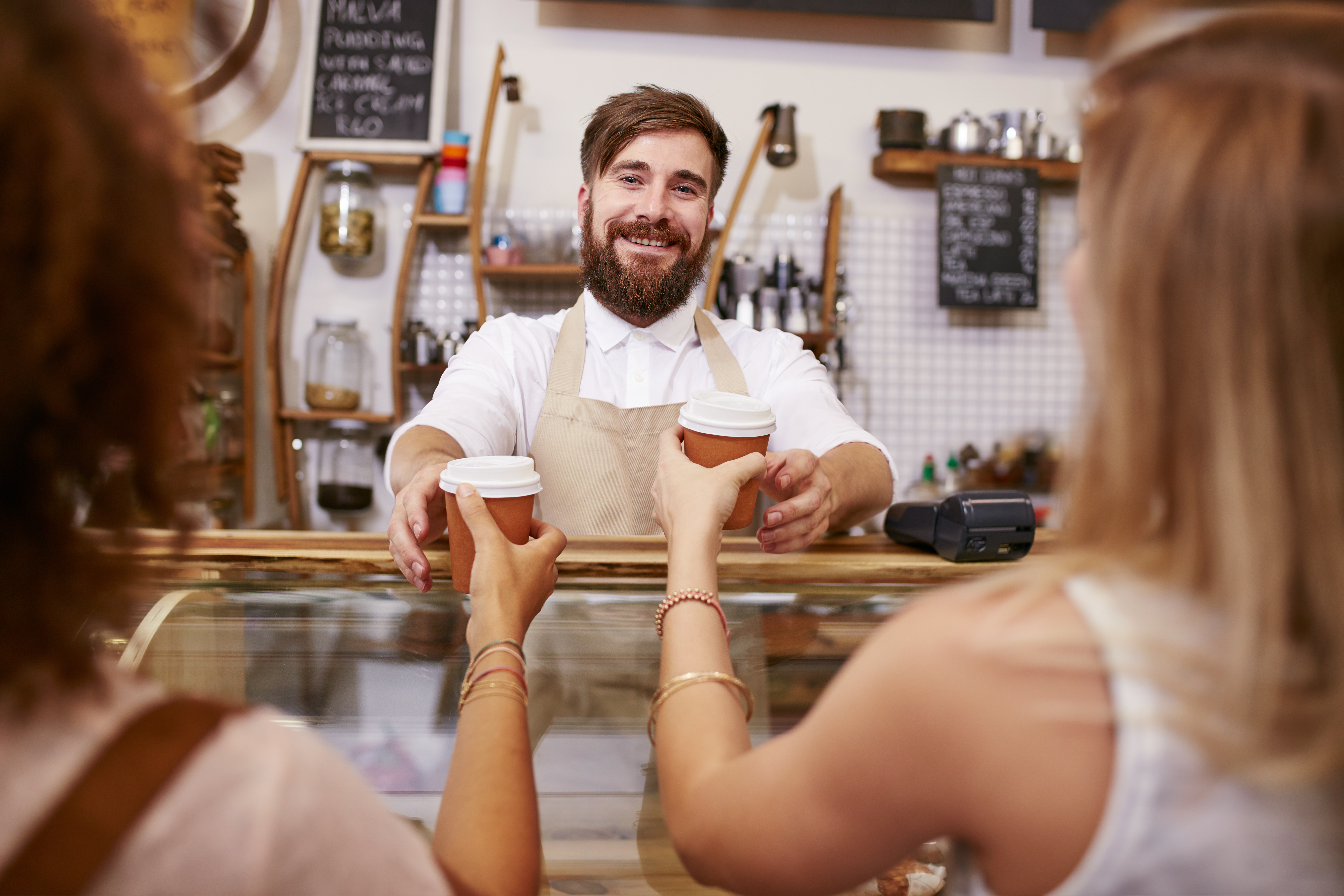 a friendly man serving two women coffee